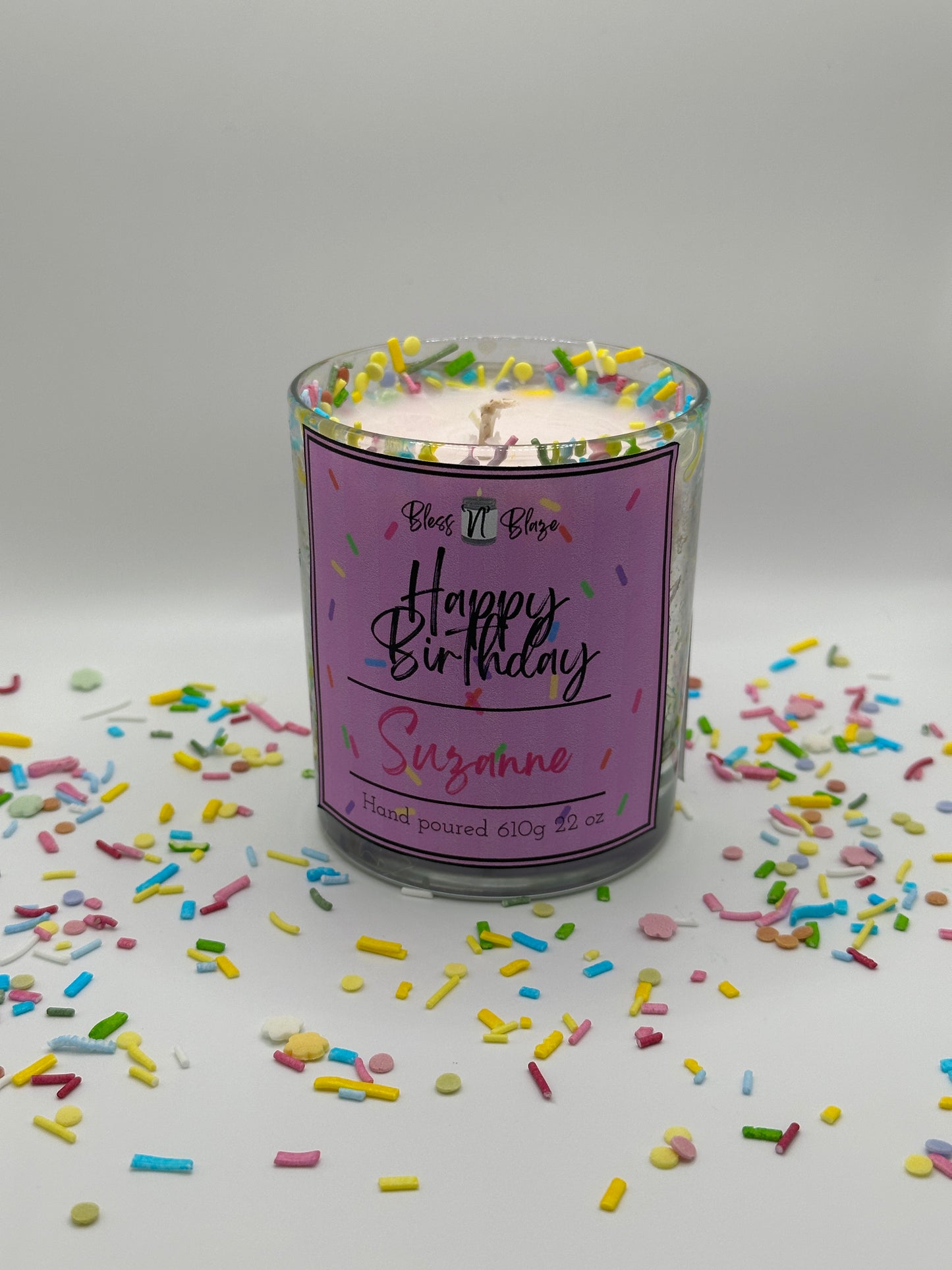 Candle In container with colorful sprinkles on a white background